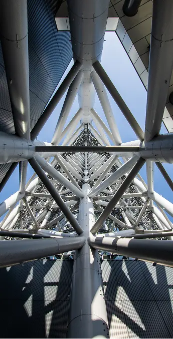青空を背景に、東京スカイツリーの白い鉄骨構造を真下から見上げた、幾何学的な網目状のデザイン。