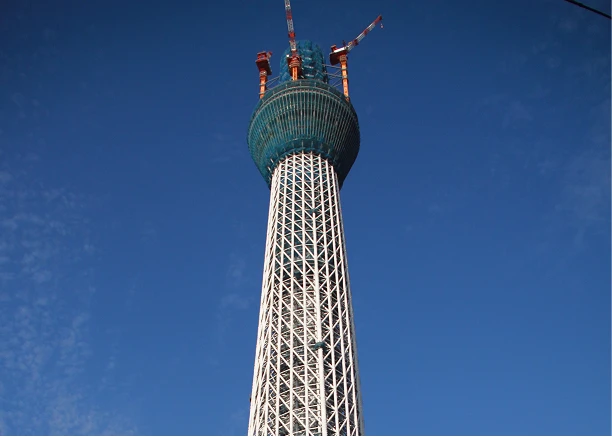 建設途中の東京スカイツリー。最上部に設置されたクレーンと、組み上げられていく白い鉄骨。