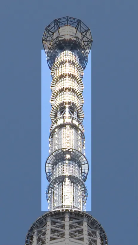 青空を背景に、東京スカイツリーの最上部アンテナ付近を見上げた写真