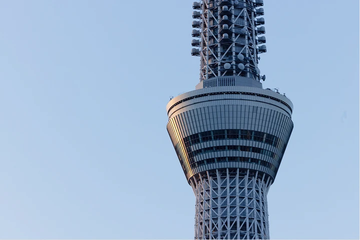 外壁前で作業着姿の人物が清掃や点検作業を行っている様子