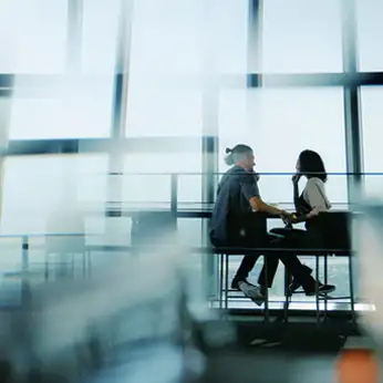 大きな窓辺で向かい合い会話する男女のシルエット