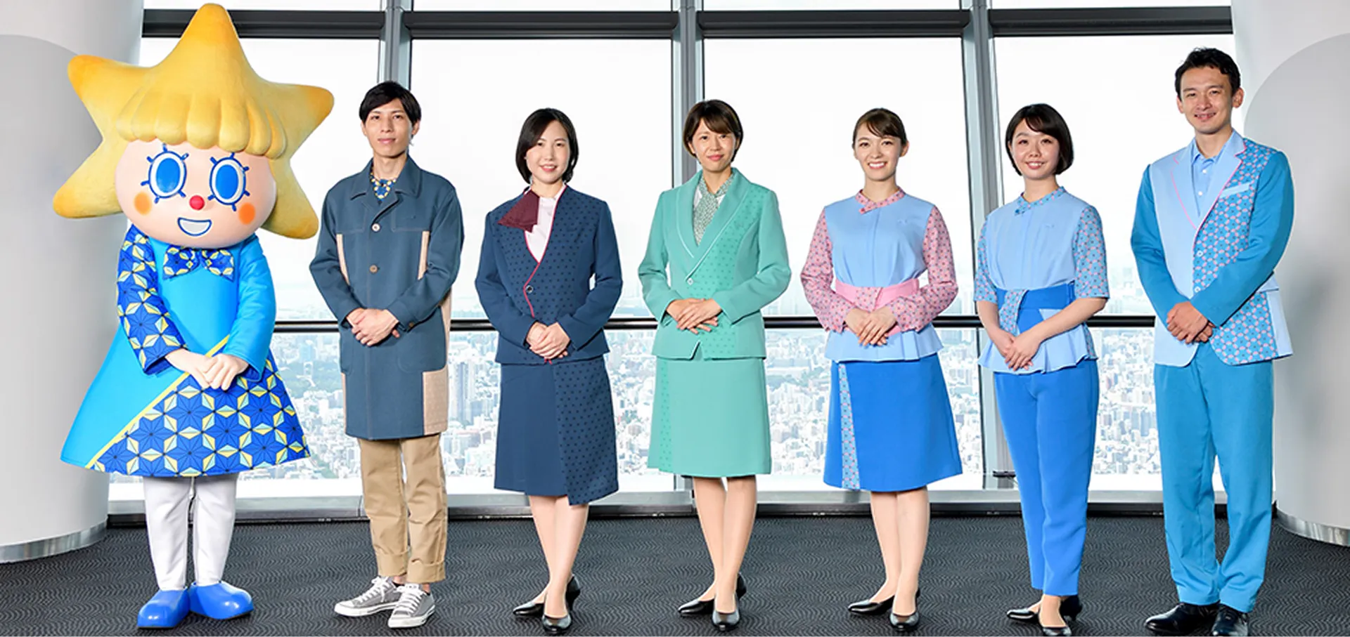 A group photo showing TOKYO SKYTREE's Official characters, "Sorakara-chan," and six Staff from various departments, all wearing newly designed Uniform.