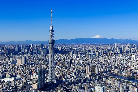 東京スカイツリーの全景と、遠くに見える富士山。青空の下に広がる東京の街並み。
