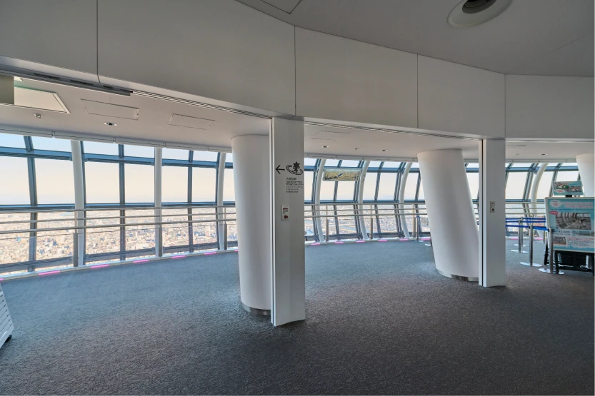 外光が差し込む明るい日中の天望回廊入口付近と、窓の外に広がる街並み