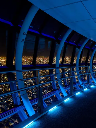 青いLED照明が床に沿って光る、近未来的な夜の展望通路。