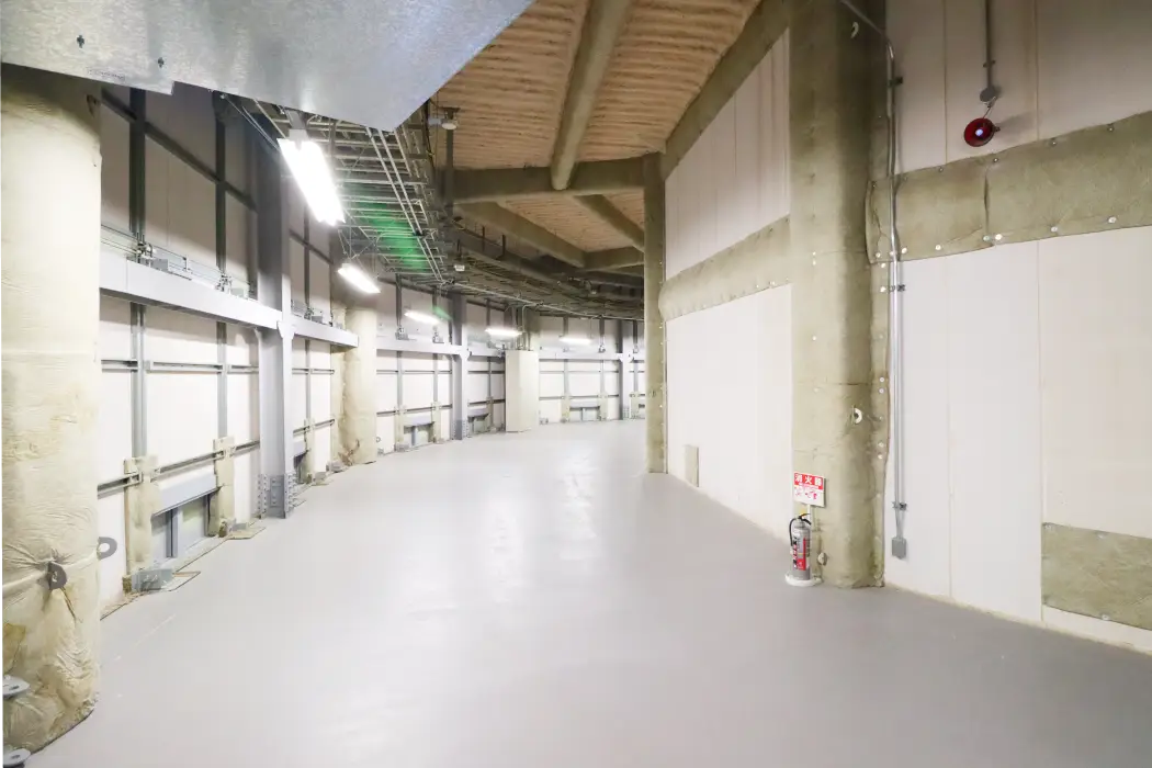 カーブした白い内壁に沿って続く、照明付きの長い屋内通路スペース