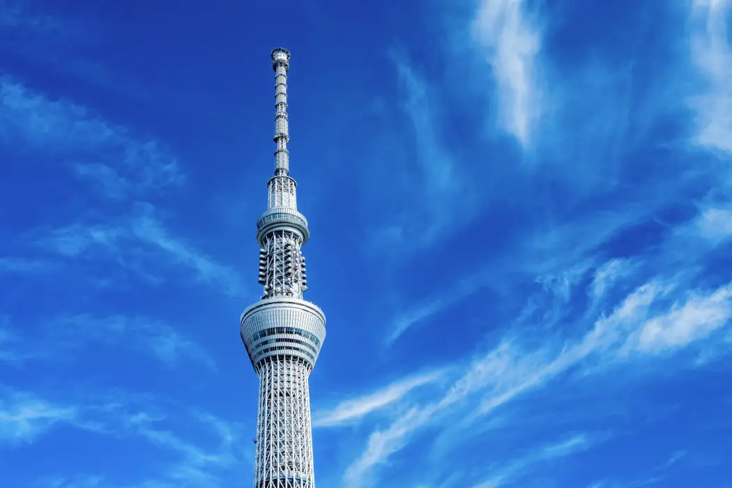 雲が広がる青空を背景にした、東京スカイツリー最上部のゲイン塔と送信アンテナ群