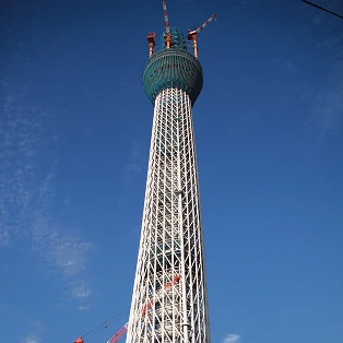 建設途中の東京スカイツリー。最上部に設置されたクレーンと、組み上げられていく白い鉄骨。