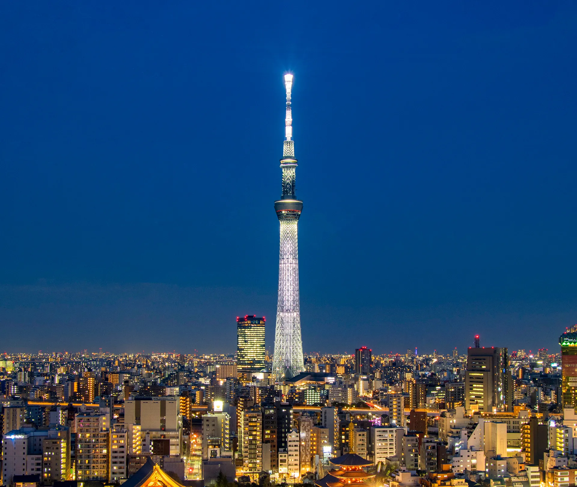 ブルーモーメント（薄明）の時間帯にライトアップされた東京スカイツリー。足元にはオレンジ色に輝く街の灯りが広がっている。