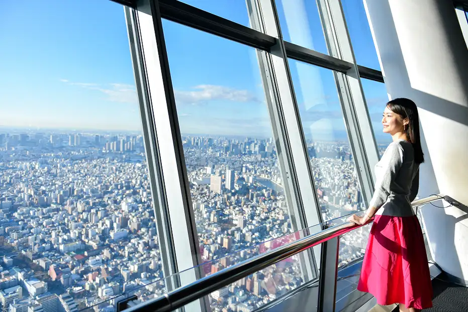 展望デッキの窓から東京の街を眺める女性