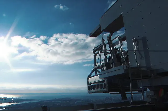 強い日差しが差し込む中、スカイツリーの高い場所にある専用格納庫に設置された清掃用ゴンドラ。