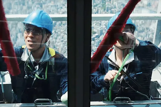 青いヘルメットを被った清掃員が、手に持った赤い清掃道具を動かしている様子。