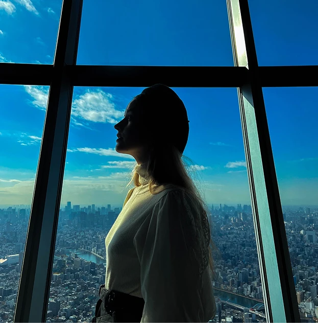 窓の外の青空と街並みを背景にした女性の横顔のシルエット