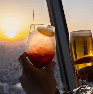 夕暮れの街並みを背景にグラスで乾杯する様子