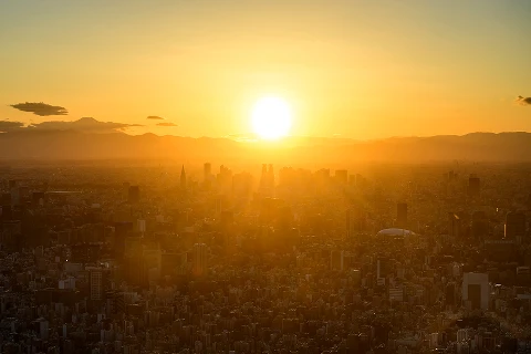 夕焼けに染まる空と太陽の光に包まれた街並みの風景