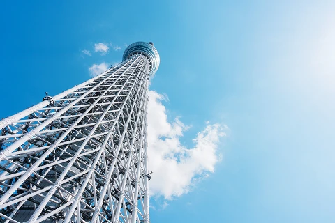 澄み切った青空に向かって伸びる白い東京スカイツリーを下から見上げた様子