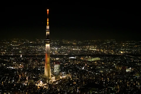 夜の暗闇にオレンジ色にライトアップされた東京スカイツリーと街の夜景