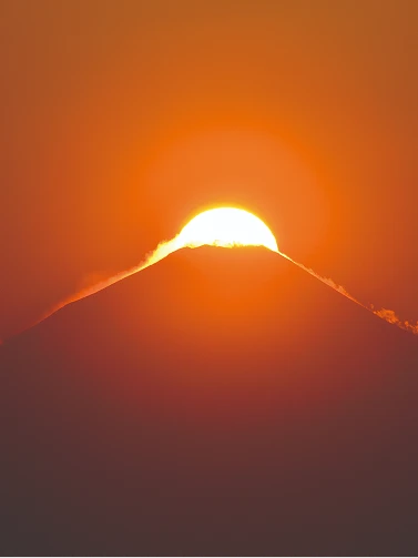 オレンジ色に染まる空と、富士山の山頂に太陽が重なるダイヤモンド富士