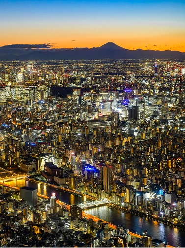夕暮れ時の美しいグラデーションの空に浮かぶ富士山のシルエットと輝く街の明かり