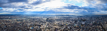 雲の隙間から光が差し込む街並みのパノラマ風景