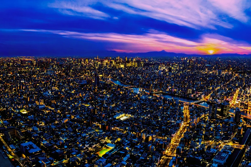 夕暮れ時のマジックアワーに輝く東京の夜景と、遠くに見える富士山のシルエット