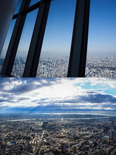 展望台の窓越しに広がる街並みと、雲の間から光が差し込む昼間の東京の景色