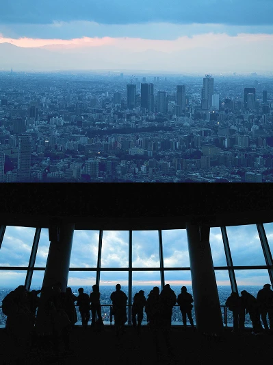青く染まる夕暮れ時の街並みと、展望台からの景色を鑑賞する人々のシルエット
