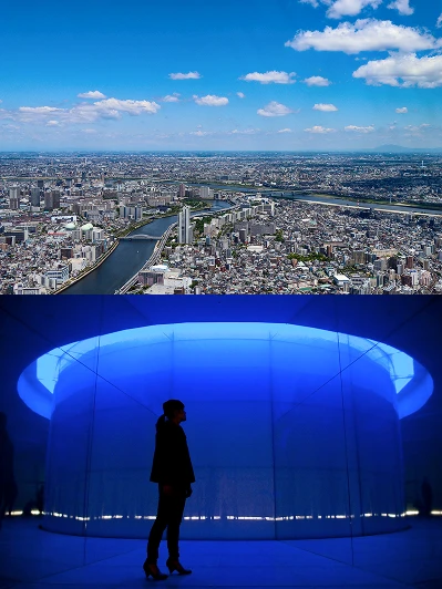 隅田川が流れる晴天の東京の街並みと、青い光に包まれた展望フロア内の展示装飾