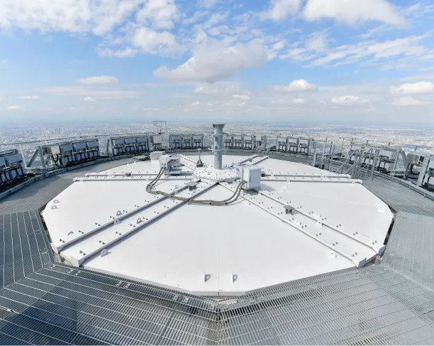 東京の街並みを見下ろす、スカイツリー頂部に設置された広大な円形プラットフォームと各種観測設備の外観。