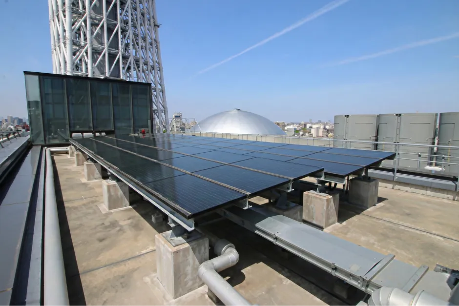 東京スカイツリータウンの建物の屋上に、整然と並べて設置された太陽光発電用のソーラーパネル群の全景。
