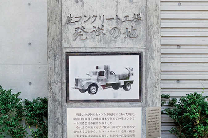 「生コンクリート工場発祥の地」の石碑。中央にクラシックなミキサー車のイラストがはめ込まれている。
