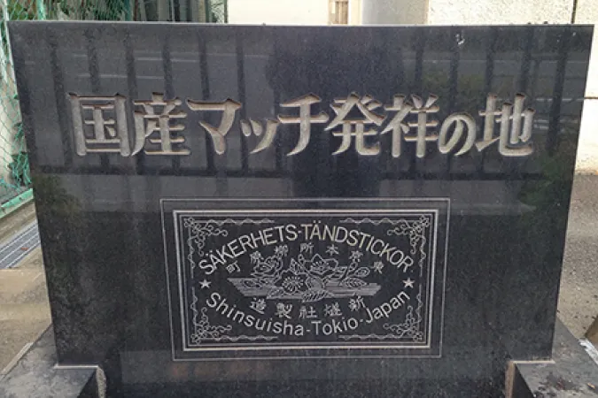 「国産マッチ発祥の地」の記念碑。黒い石碑に歴史を感じさせるマッチのラベルデザインが刻まれている。