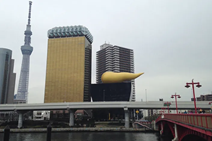 隅田川越しに見る現在のアサヒグループ本社ビルと、隣接する「スーパードライホール」の屋上の巨大なオブジェ。背景には東京スカイツリーがそびえ立つ。
