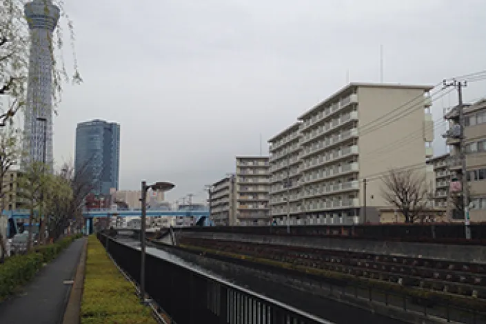 東洋紡績の跡地に建てられた現在の都営住宅。背後には東京スカイツリーがそびえ立ち、かつての工業地帯が住宅地に変わった様子を示している。