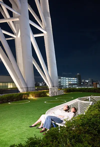 夜の芝生広場のネットベンチに寝そべる女性