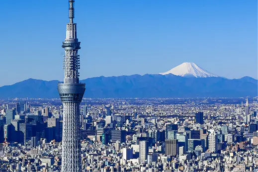 青空を背景に、遠くに富士山を望む東京スカイツリーと東京の街並みの俯瞰画像