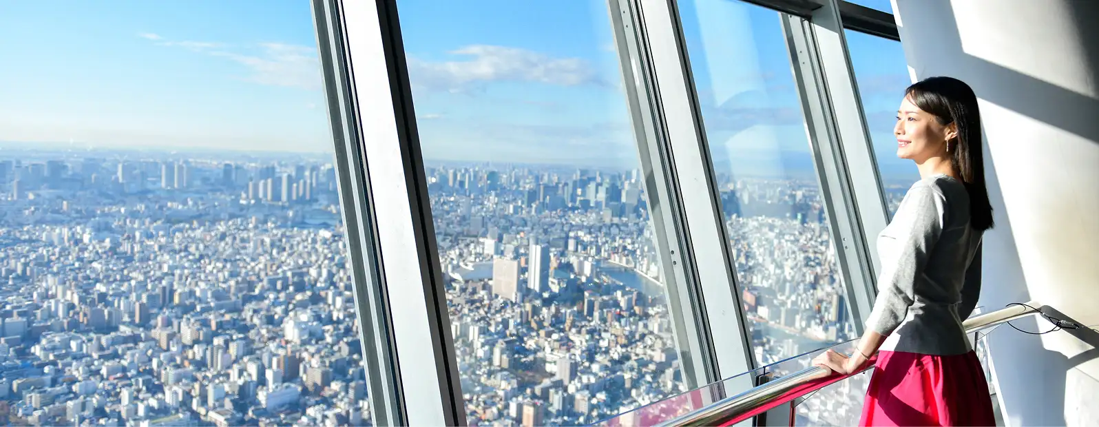 展望デッキの窓から東京の街を眺める女性