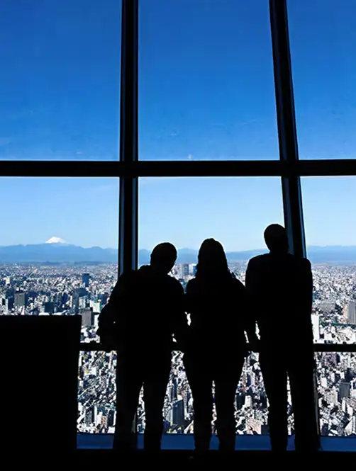 展望フロアの窓から景色を眺める来場者のシルエット