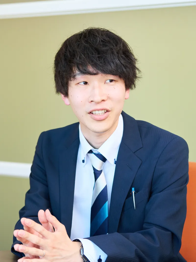 業務の幅広さについて説明するK.Kさんのポートレート