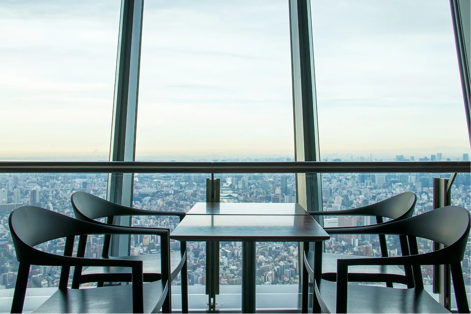 大きな窓の向こうに広がる空と街を独占できる、落ち着いた雰囲気のテーブル席