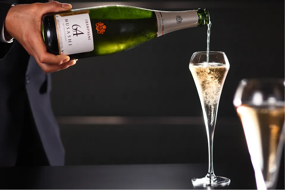 繊細な泡が立ち上がるシャンパンが、フルートグラスに注がれる様子。