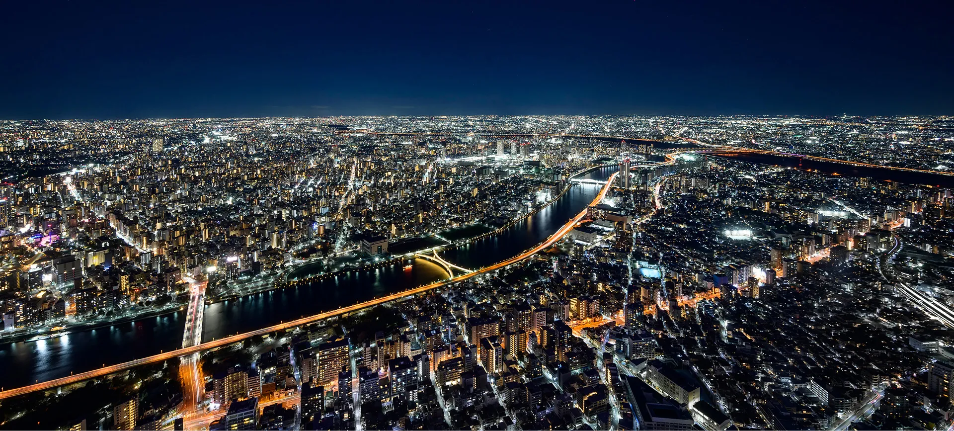 夜の光り輝く街並みと川に架かる橋。