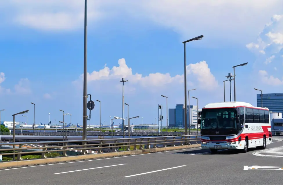 空港の滑走路エリアを走る赤と白のリムジンバス